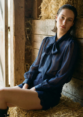 Cami NYC Rema Jacquard Top Navy. Model is posing in product on hay. 