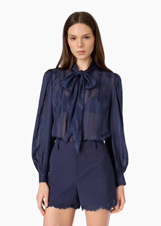 Cami NYC Rema Jacquard Top Navy. Model is posing in front of a white background in the top. 