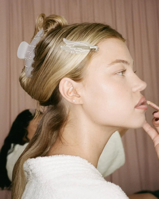 Emi Jay Angel Popstar Clips in Lilac Smoke. Model applying makeup with clip in her hair. 