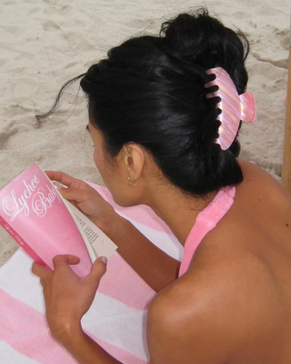 Emi Jay Big Effing Claw Clip in Lychee Baby. Model wearing hair clip while reading. 