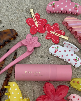 Emi Jay Cloud Popstar Clips in Hibiscus Beach. Hair clips are displayed on sand next to other Emi Jay products.