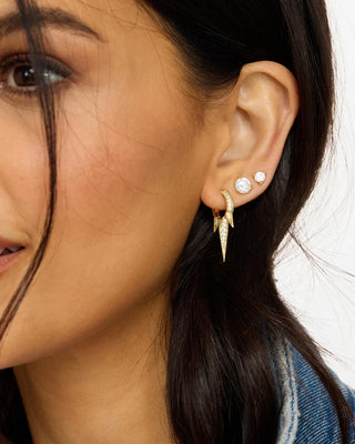 Gold pavé triple spike earrings styled on model with soft glam makeup and white tee