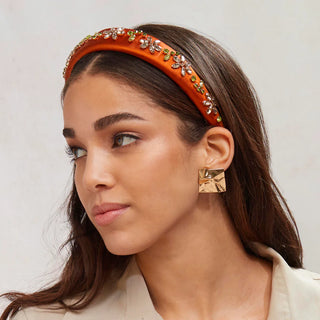 Model wearing Lele Sadoughi Sienna Meadow Alice Crystal Garden Flower Headband, featuring colorful floral accents and crystals on a wide, fabric-covered headband.