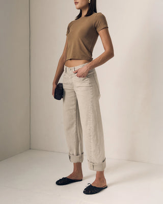 Le Jean Selena Crop Cuffed Mid Rise. Model is turned to the side posing in the product in front of a white background.