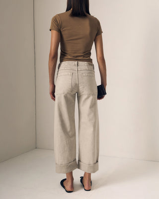 Le Jean Selena Crop Cuffed Mid Rise. Model is turned around and posing in product in front of the white background.  