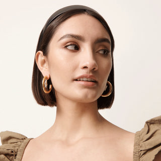 Lele Sadoughi Jet Faux Leather Bessette Headband. Model is wearing the product shot on a white background. 