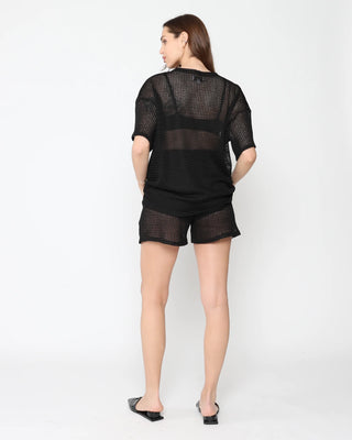 Ripley Rader Black Fishnet Lounge Shorts. Model is wearing product posing on a white background with her back to the camera. 