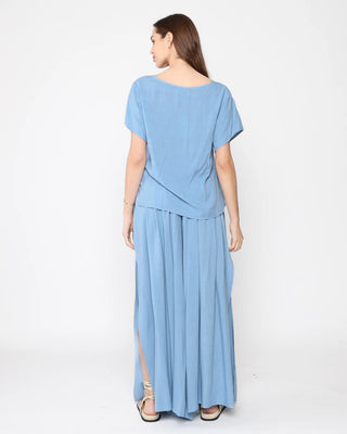 Ripley Rader Chambray Linen Flowy Pant. Model is wearing product posing on a white background with her back towards the camera. 