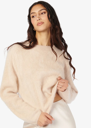 Woman wearing a beige sweater , the cami nyc niall in oat, on a white background