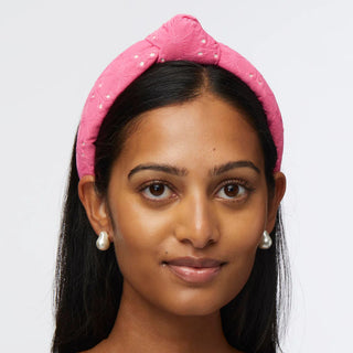 woman is wearing Lele Sadoughi slim knotted headband in vibrant fuchsia eyelet fabric with embroidered floral detailing