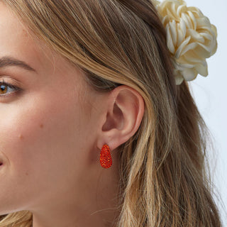 Model wearing Lele Sadoughi Scarlet Pavé Dome Mini Hoop Earrings, featuring bold red mini hoops covered in sparkling pavé crystals for a striking pop of color.